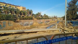 Vorne beschädigte Brücke, dahinter Abflusskanal mit Schlamm und Graffiti in Valencia